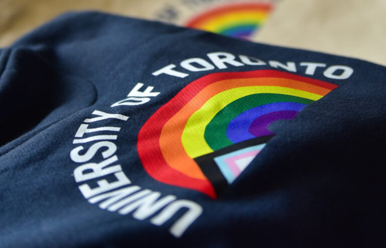 A folded University of Toronto sweater featuring a rainbow image of the progress pride flag.