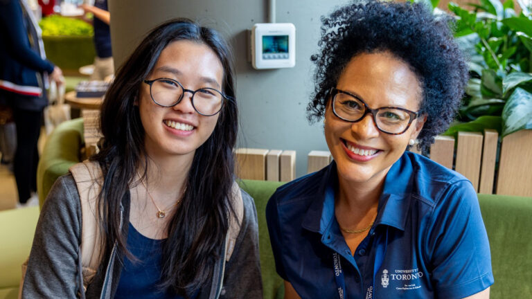 Two people seated on a green couch in the common area of the Experiential Learning Commons Centre