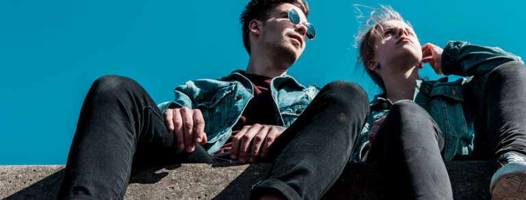 Two people are seated together outside on a sunny day.