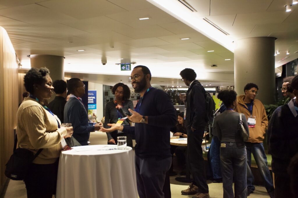 Group of Black alumni gathered in a restaurant talking and mingling with drinks in hand