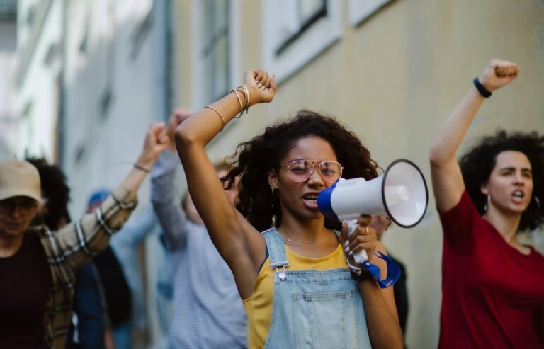 Young woman at front of group with a mega phone, fist in the air